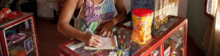 Mujer en una tienda anotando en una libreta de recibos.